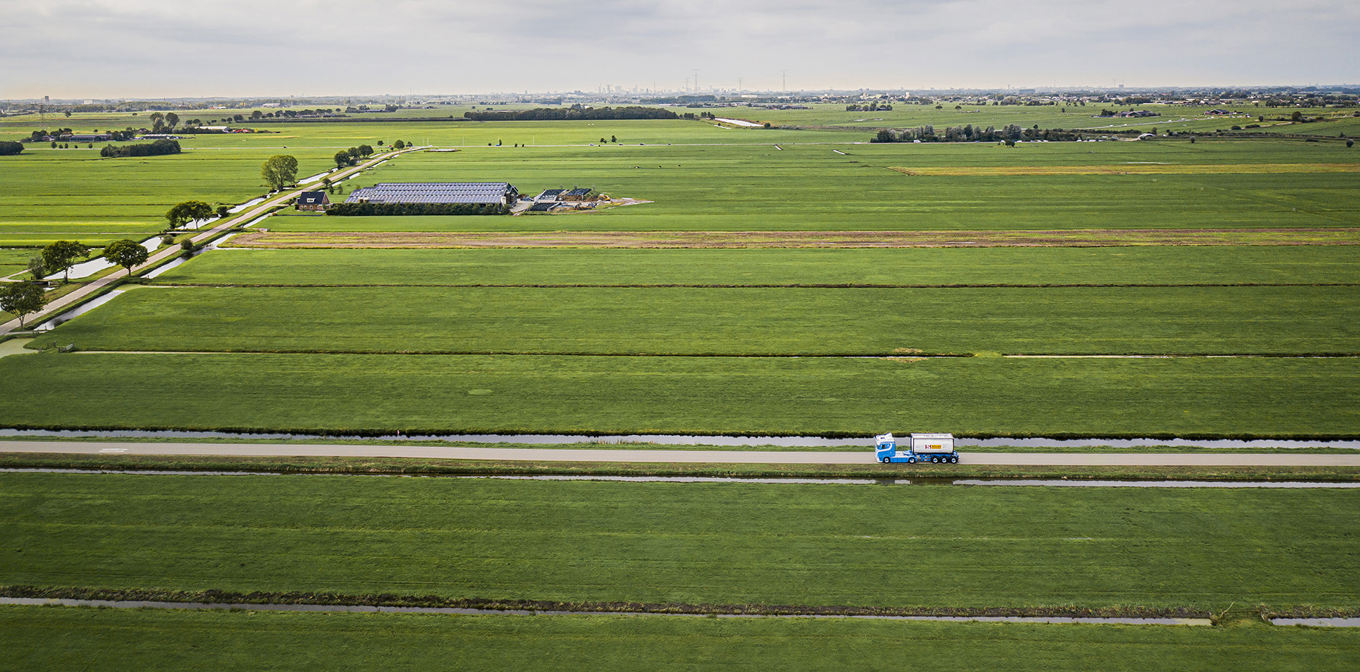 Truck driving with tank container in fields 