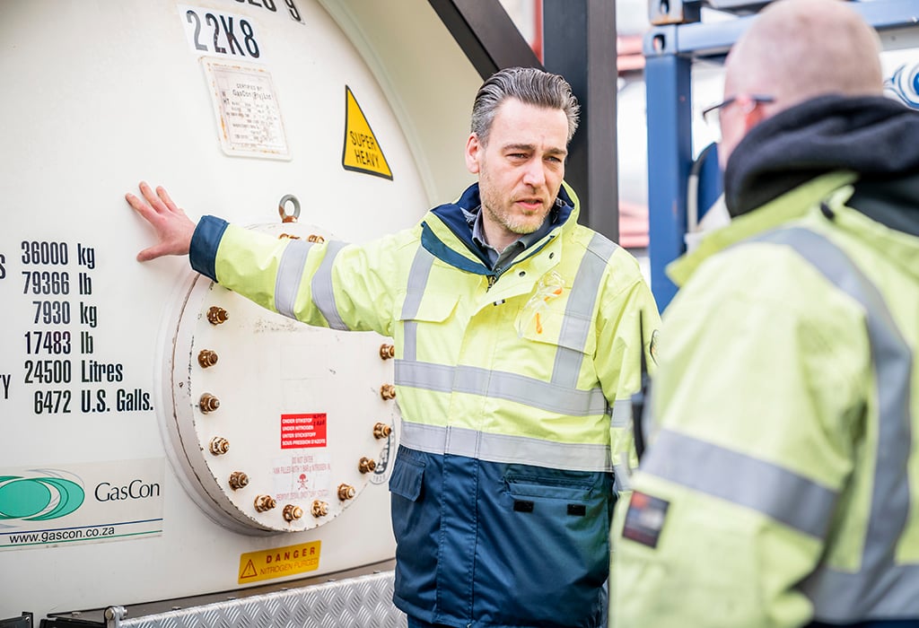Tank container specialist standing next to gas tank container