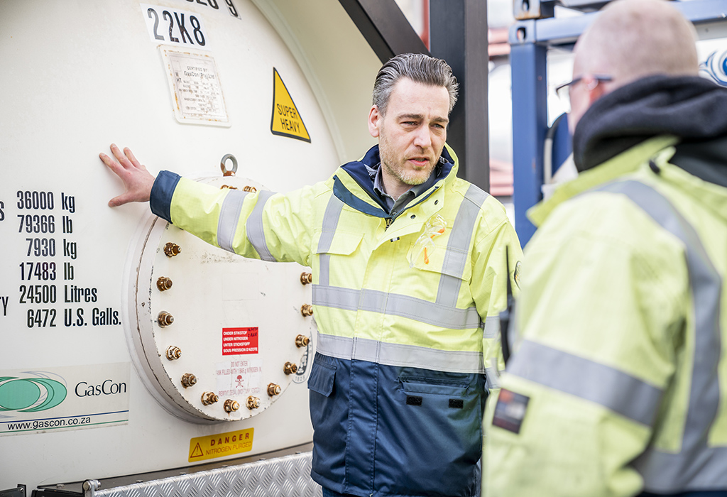 Tank container specialist standing next to gas tank container Tank container specialist standing next to gas tank container