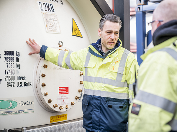 Tank container specialist standing next to gas tank container Tank container specialist standing next to gas tank container
